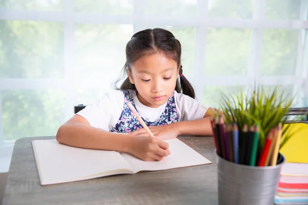 Basisschool meisje lezen en schrijven boek in de klas — Stockfoto