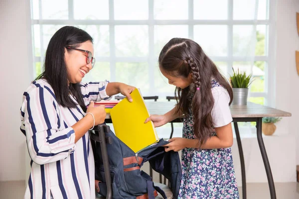 Mamma hjälpa grundskolan flicka packning böcker till väskor — Stockfoto