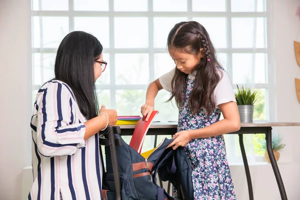 Mamma hjälpa grundskolan flicka packning böcker till väskor — Stockfoto