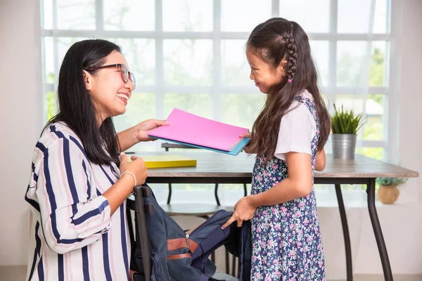 Mamma hjälpa grundskolan flicka packning böcker till väskor — Stockfoto