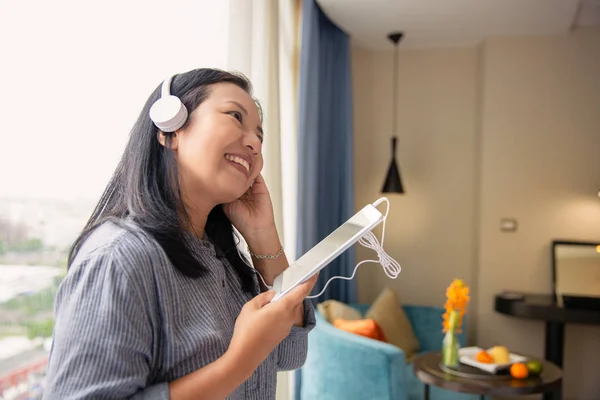 Gorgeous glad asiatisk kvinna Headset lyssnar musik från bordet — Stockfoto