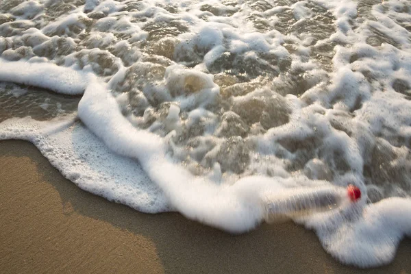 Rörelseoskärpa av plastflaska på stranden med stänk havet WA — Stockfoto