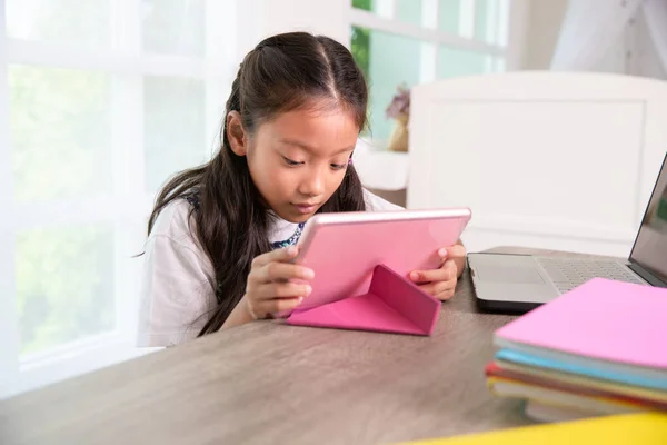 小さなアジアの女の子は昼間に自宅でタブレットPCを楽しむ — ストック写真