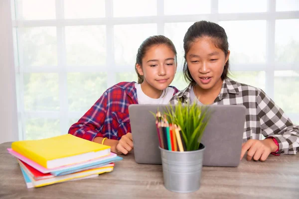 Two teenager students girls watching computer laptop, Home online study or Work from home concept