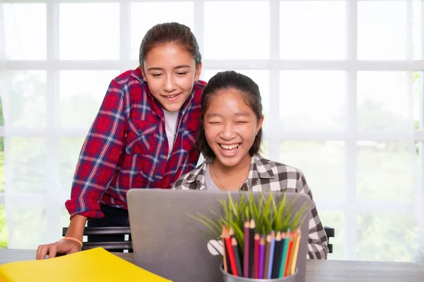 Two teenager students girls watching computer laptop, Home online study or Work from home concept