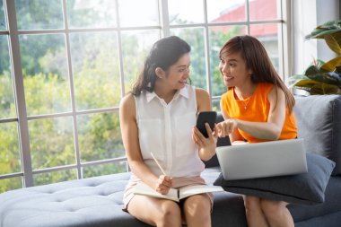 İnternetten akıllı telefon alışverişi yapan iki Asyalı kız arkadaş. Yeni normal yaşam tarzı kavramı.