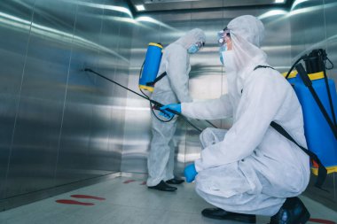 Virüs korumalı süit ve maske takan alkol temizleme 19 enfekte asansör alanı, virüs dezenfeksiyonu konsepti