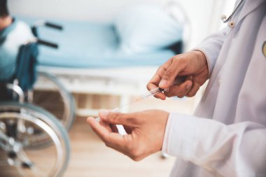 Engelli hastaya şırınga hazırlayan doktor.
