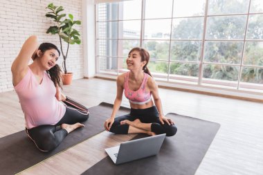 İki Asyalı kadın dizüstü bilgisayar internetten yoga eğitimi alıyor. Yeni normal egzersiz yaşam tarzları.