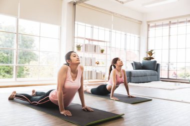 Yoga dersinde gerinen iki Asyalı kadın.