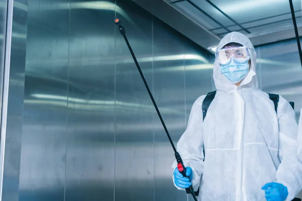 Man in virus protective suite and mask spraying alcohol cleaning covid19 infected area, Virus disinfection concept