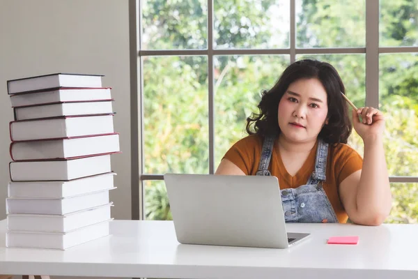 Asian fat woman with laptop computer and books working from home