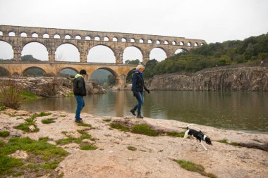 Pont du Gard Fransa 1 Nisan 2013 Güzel Roma Köprüsü Pont du Gard, UNESCO dünya mirası geçmişi ile Gardon nehrinin kenarında duran köpeği olan genç bir çift..