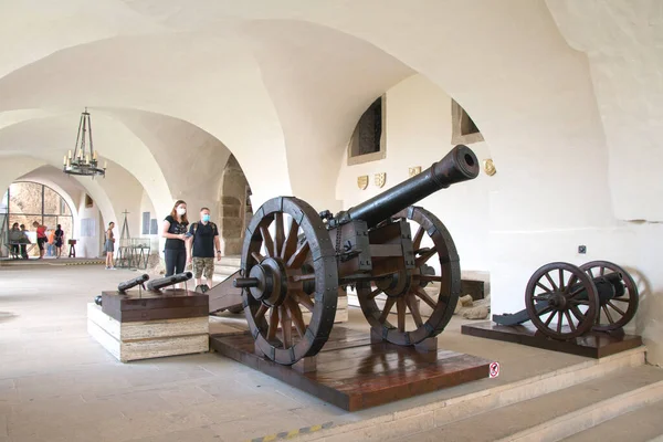 Spisk Podhradie Slovakya 31 Temmuz 2020 Spissk Hrad kalesinin müzesinde eski ahşap tekerlekli toplar. Gotik kemerli sergi salonunda, ziyaretçiler siyah bir maske takarlar..