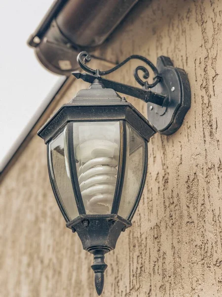 A photo of a vintage street lamp mounted on the wall of a house with sepia effect.Application in the manufacture and sale of street lamps and other purposes.