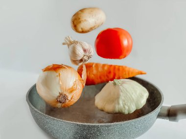 Sebze güveci için tavanın üzerinde süzülen sebzeler. Yemek pişirme konsepti.