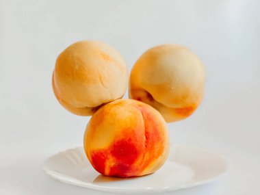 Üç güzel şeftali beyaz bir tabağın üzerinde uçuyor. Sağlıklı yemekler, meyveler.