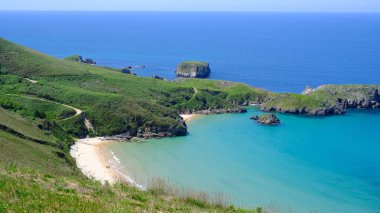 İlahi yüksek açılı bir çekim İspanya 'nın Asturias kentindeki sakin turkuaz sularıyla tenha Torimbia plajını yakalıyor. Kumsal yemyeşil yamaçlarla kayalık yamaçların arasına kuruludur.