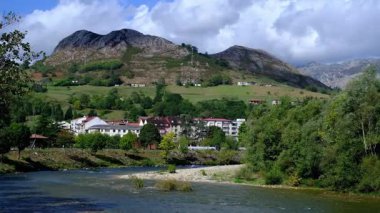 İspanya 'nın Asturias kentindeki Arriondas kasabasının içinden sakin bir nehrin aktığı pitoresk bir videosu. Kamera, geleneksel mimari astarlı bir dizi büyüleyici binayı yakalar.