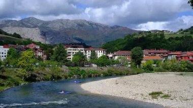 İspanya 'nın Asturias kentindeki Arriondas kasabasının içinden sakin bir nehrin aktığı pitoresk bir videosu. Kamera, geleneksel mimari astarlı bir dizi büyüleyici binayı yakalar.