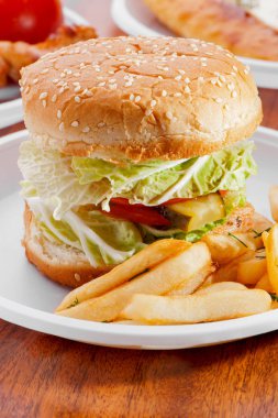Burger sebze ve Kızarmış patateslerin üzerine beyaz tabak yakın çekim fast food Cafe 