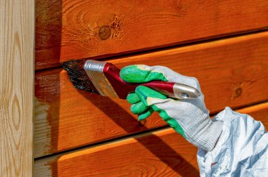 Turuncu işlemeli ahşap duvar boyası boya fırçası ve eldiven kapaklı yakın plan.  