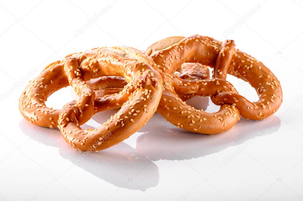 two pretzels sprinkled with sesame seeds close-up isolated on white background with reflection 