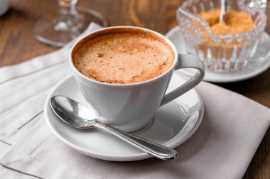 kaşık, tabak, kahverengi şeker kase ve ahşap masa üzerinde keten peçete ile kahve yakın çekim fincan 