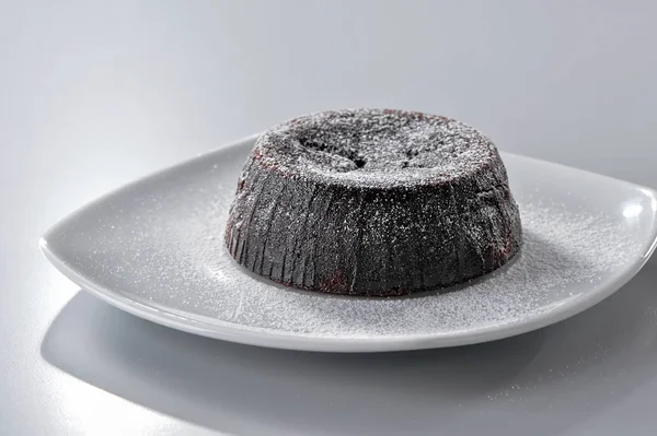ブラウニーケーキの上には 中性の背景を持つ白い皿の上に粉砂糖のクローズアップ — ストック写真