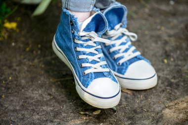 Beyaz bağcıklı şık kot ayakkabılar. Arka planda doğal çekimler.