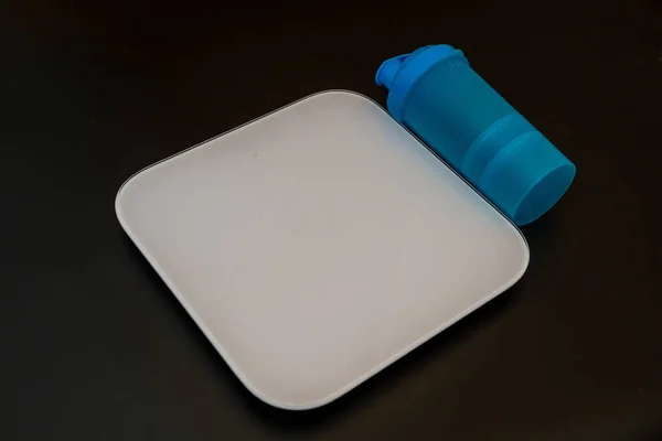 Electronic white scale with sport bottle on a black background