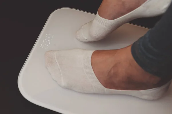 View of female feet in white socks stands on an digital scale. Diet Concept