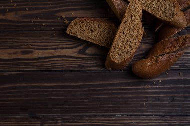 Siyah ekmek. Dilimlenmiş koyu baget, koyu kahverengi tahtaların ahşap zemininde yatar..