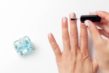 Dişi eller tırnaklarına yağ sürer. Kütikül yağı. Beyaz bir arka planda izole edilmiş. Yukarıdan bak. Yüksek kalite fotoğraf