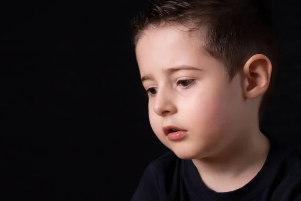 Portret van een droevige jung jongen geïsoleerd op zwart — Stockfoto