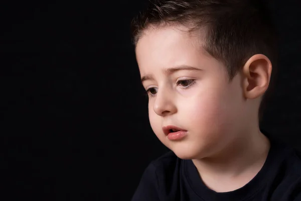 Porträtt av en ledsen jung pojke isolerad på svart — Stockfoto