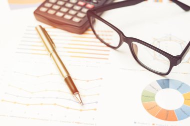 Ofisteki masadaki grafiklerden hesap makinesi ve kalem ile veri analizi. iş kavramı.