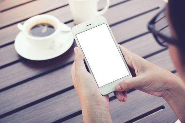 Kafede boş ekranlı akıllı telefonu tutan kadın. kırpma yolu.