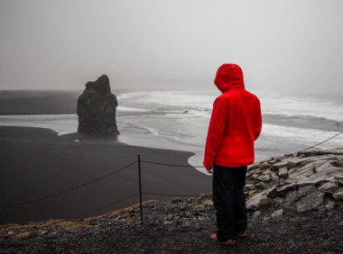 Genç gezgin balck kum plaj kaya oluşumu Kirkjufjara Beach, İzlanda için arıyor. Yağmurlu bir gün.