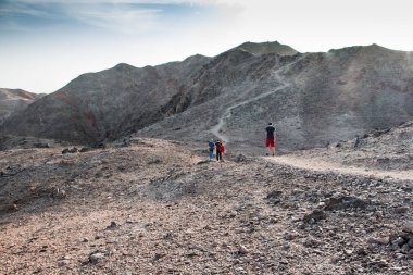 Bir grup yürüyüşçü, dağın tepesindeki çölde gün batımını izliyor. vadide kızıl deniz. Eilat dağları, Negev çölü, İsrail. Tzfahot Dağı