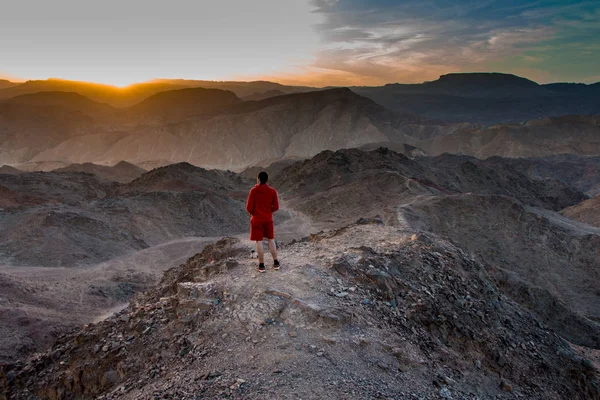 Hiker watching the sunset in the desert on the top of the mountain. red sea in the valley. Eilat mountains, Negev desert, Israel. Mount Tzfahot