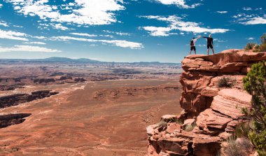 Baba ve oğul, Canyonlands Milli Parkı'nda el kaldırarak bir uçurumda. Grand Overlook noktası. Özgürlük ve mutluluk kavramı.
