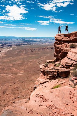 Baba ve oğul, Canyonlands Milli Parkı'nda el kaldırarak bir uçurumda. Grand Overlook noktası. Özgürlük ve mutluluk kavramı.