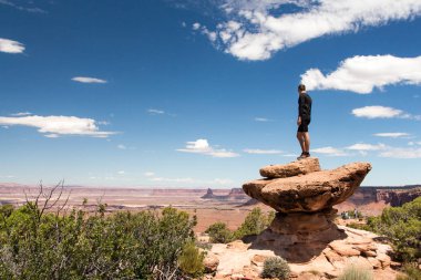 Canyonland Milli Parkı Grand Overlook bakış açısında bir uçurumun kenarında genç yürüyüşçü adam
