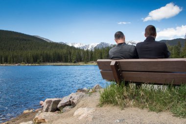 Father and son resting on a bench in Echo lake park, Colorado clipart