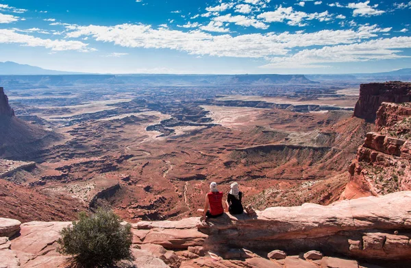 キャニオンリムに座っている観光客のカップルは キャニオンランズ国立公園 ユタ州の景色を楽しんでいます 砂漠の眺め — ストック写真