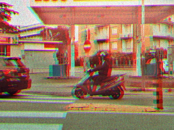 Scooterist bir motorlu scooter bir benzin istasyonu geçen