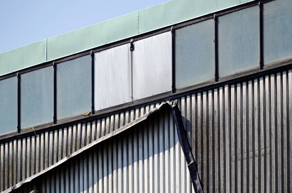 Telephoto view of a art of an abandoned industrial building with corrugated iron and glass.