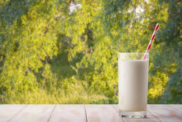 Een Glas Melk Met Een Rietje Een Natuurlijke Groene Achtergrond — Stockfoto