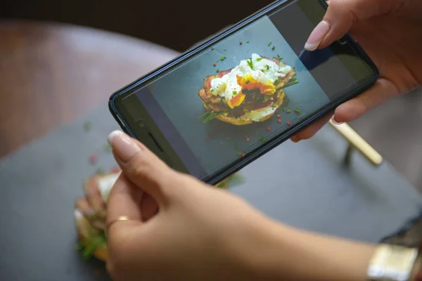 Photo of food on the smartphone. Sandwich with poached egg and bakon